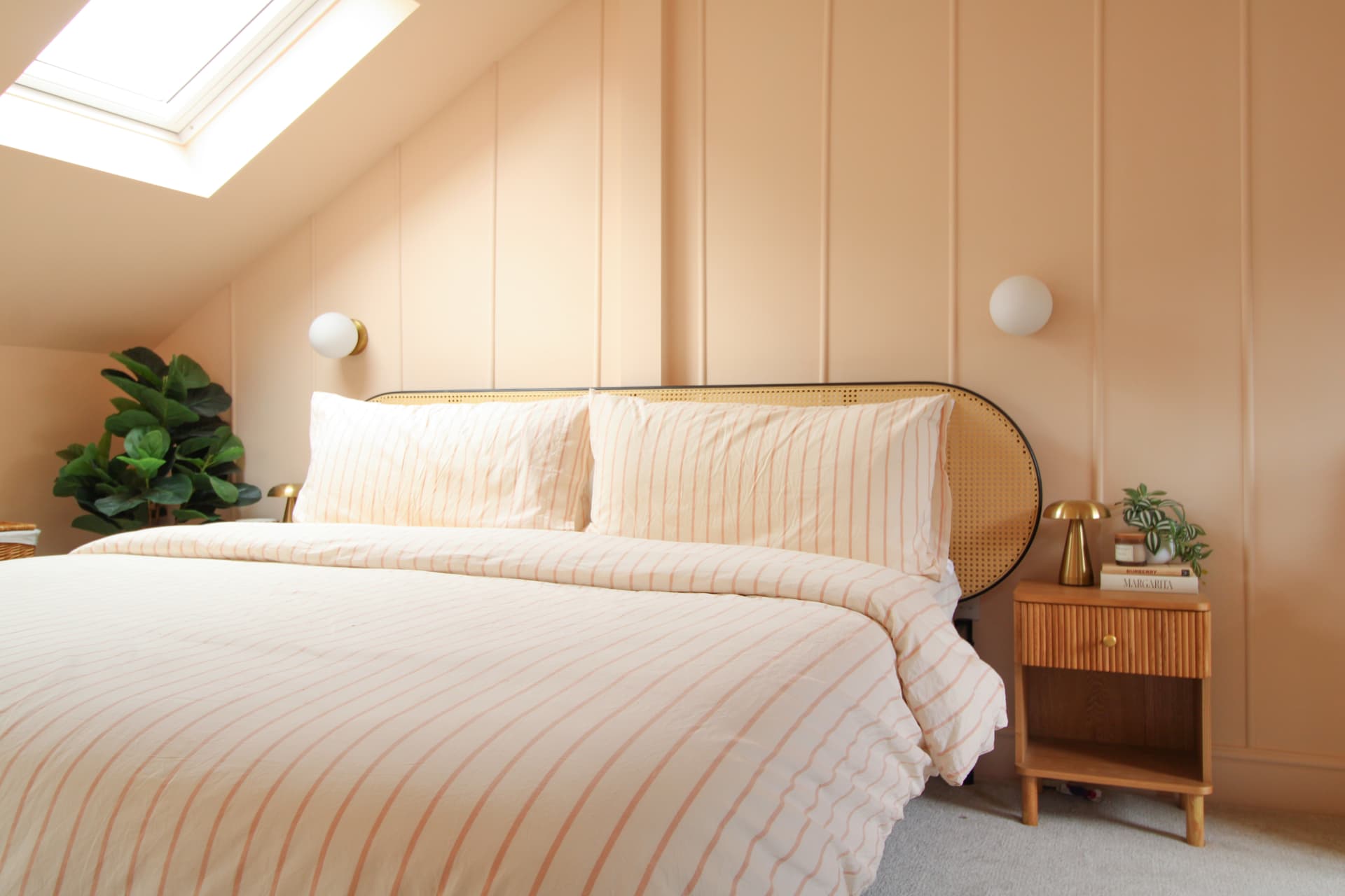 The master bedroom: peach panelled walls, skylight and rattan headboard
