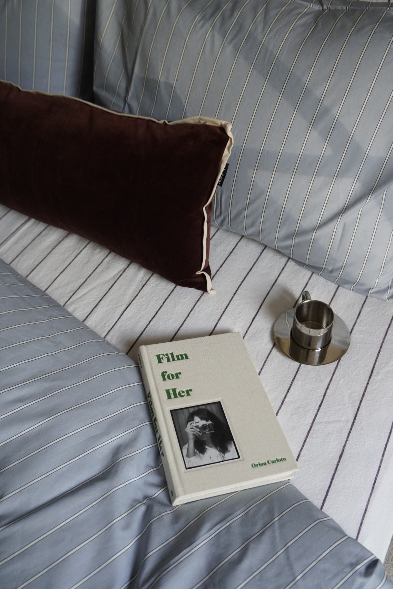 The curtain room: floor-to-ceiling cream curtains, a dark wood bed and rattan bedside table