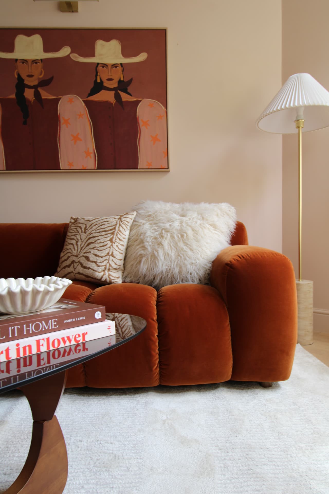 Rust velvet sofa beneath cowboy artwork in the lounge