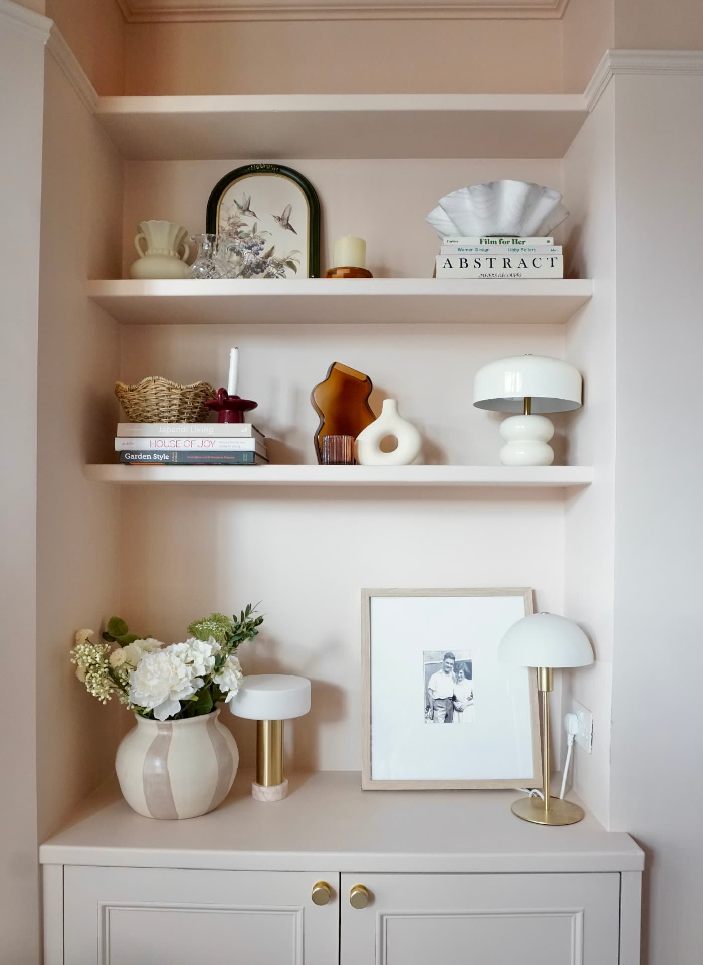 Lounge with a rust velvet sofa, built-in shelves and soft pink walls