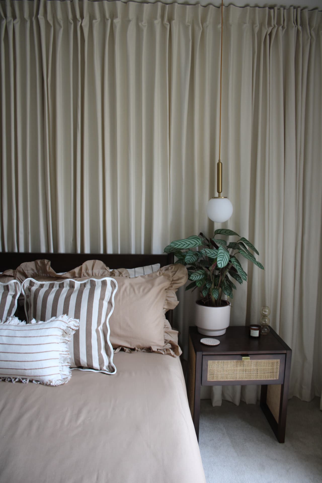 The curtain room: floor-to-ceiling cream curtains, a dark wood bed and rattan bedside table
