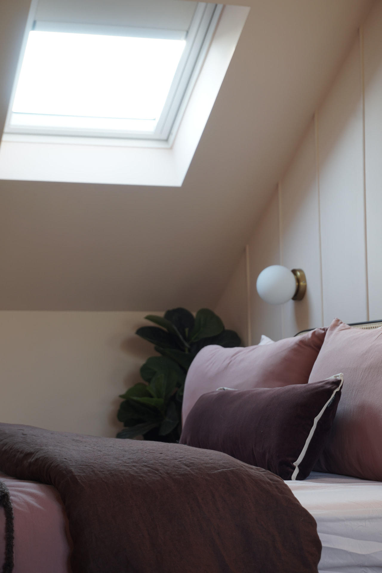 Master bedroom under the skylight with pink bedding and a chocolate throw