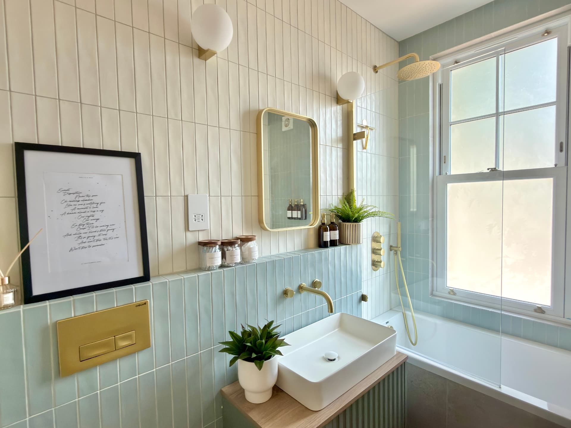 Bathroom with sage and cream tiles, brass fittings and a sash window
