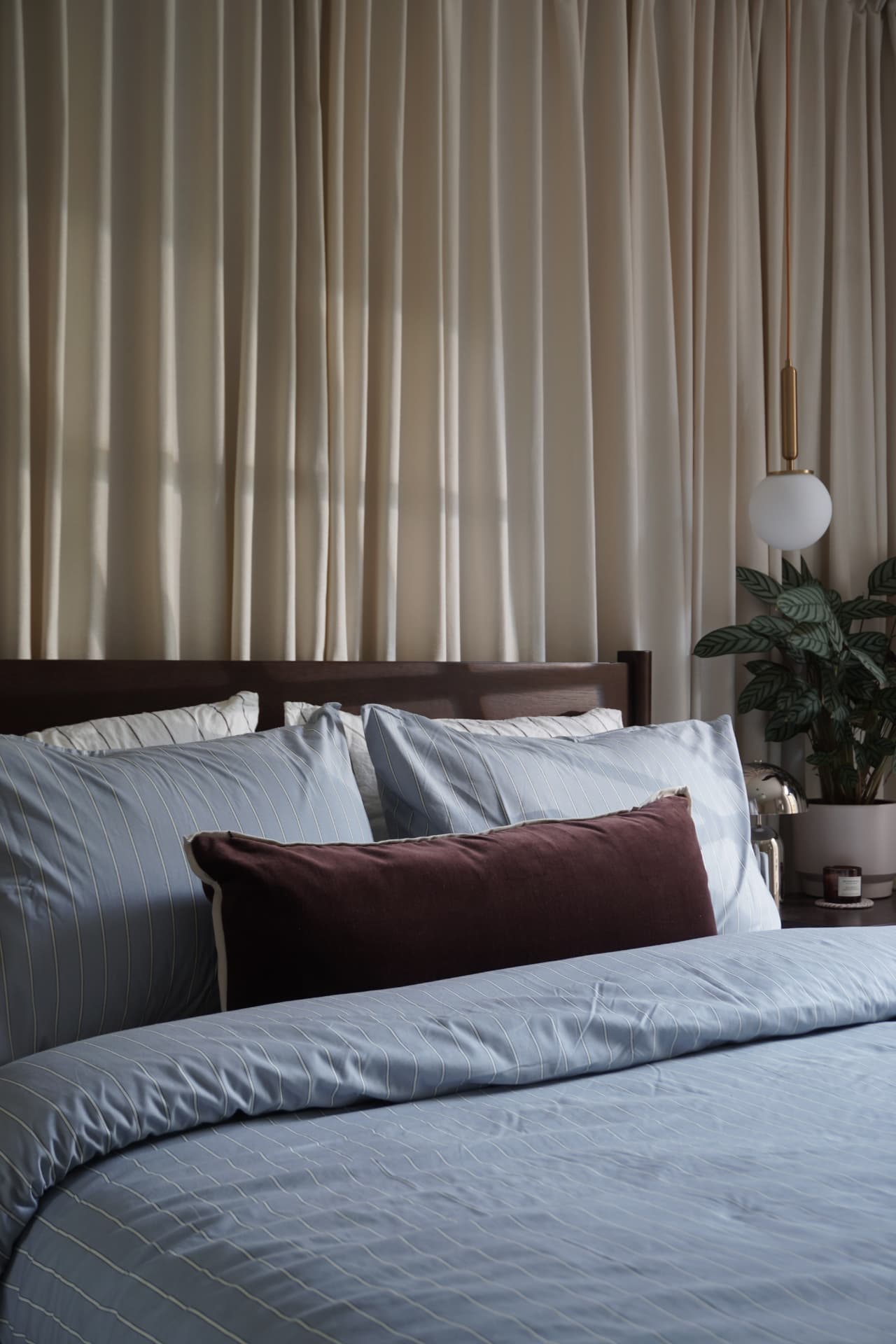 Curtain room with cream curtains, blue bedding and a dark wood bed